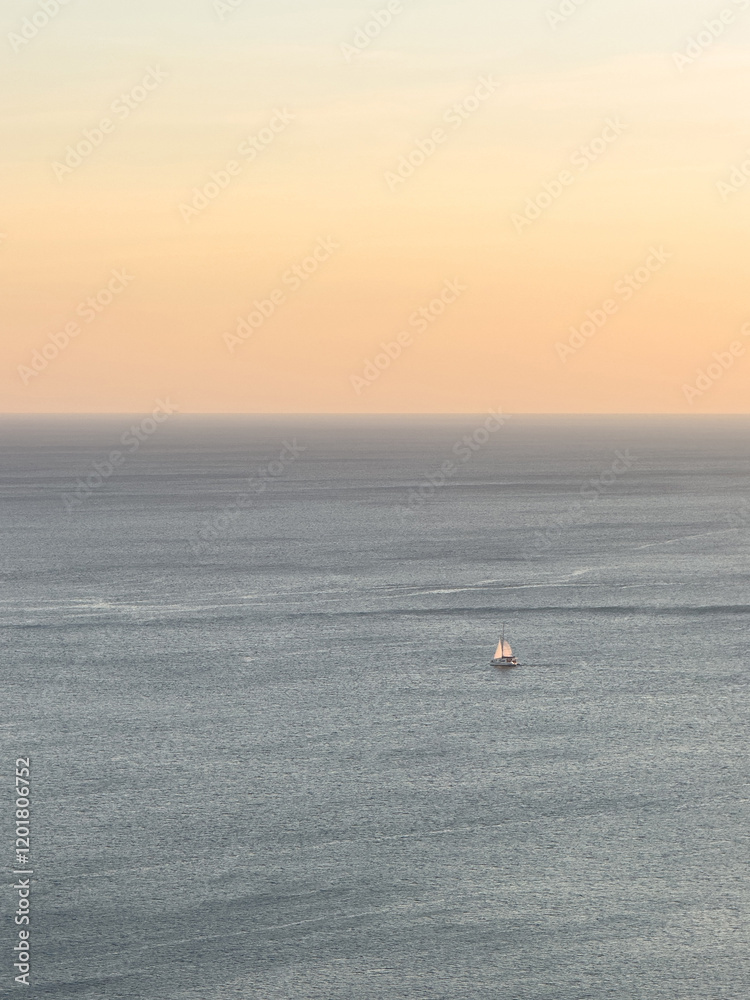 Sailing boat gliding across calm waters during sunset over ocean Sailing boat gliding across calm waters during sunset over ocean