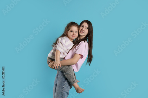 Portrait of cute sisters on light blue background photo