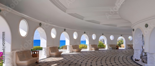 Architectural structure with arches and circular windows at Kallithea Springs, Rhodes, Greece. The open side provides sea views and surrounding greenery, with mosaic floors and stone benches. photo