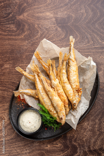 Wallpaper Mural Fried fish served on a black plate with parchment paper. Accompanied by a creamy dipping sauce and fresh herbs, creating a delicious and appetizing presentation. Torontodigital.ca