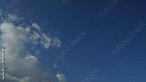 Timelapse of soft white cumulus clouds move in the blue sky. The background of light calm clouds changes shape in cloudy space. Natural background, time-lapse, copy space. 4K