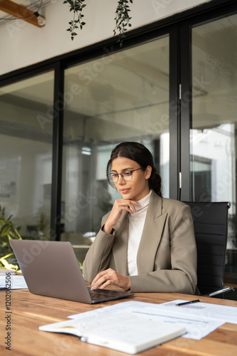 Focused professional financial it specialist latin hispanic business lady working on laptop pc sitting in office. Middle eastern indian woman using computer technology app for work online. Vertical 