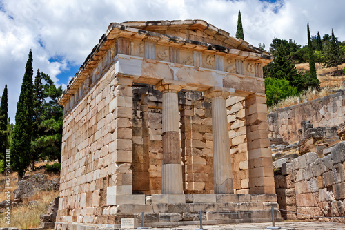 The Athenian Treasury at Delphi, Greece, showcasing its impressive Doric columns and ornate frieze, set amidst the sacred ruins of the ancient oracle