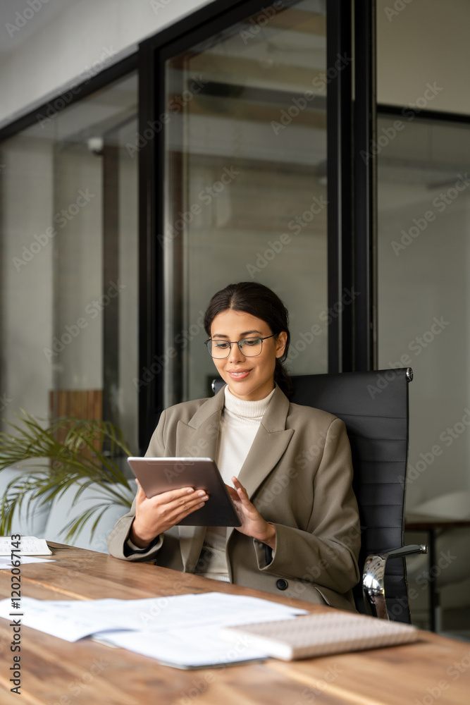 Middle eastern businesswoman holding digital tablet using tab application sitting at desk workplace in office. Young latin Hispanic professional business woman working on pad pc. Vertical, copy space Middle eastern businesswoman holding digital tablet using tab application sitting at desk workplace in office. Young latin Hispanic professional business woman working on pad pc. Vertical, copy space