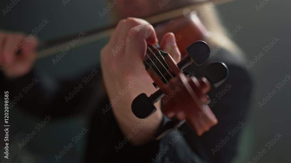 The musician plays the violin masterfully, creating a unique atmosphere and conveying his emotions through music. A talented young violinist, soloist orchestra, with long hair in a formal suit.