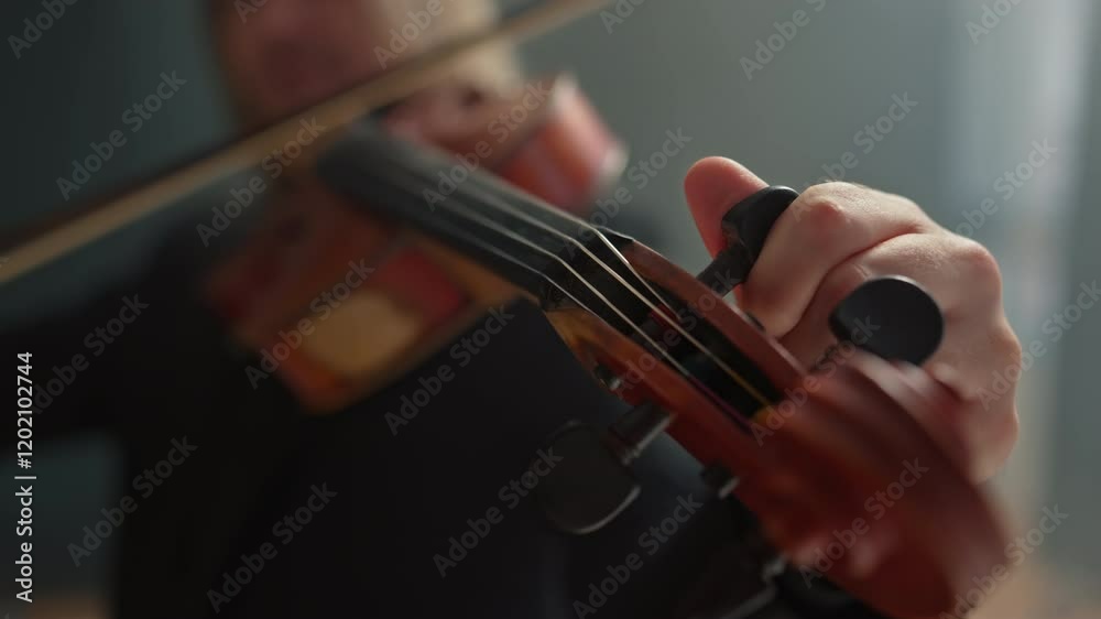 A musician turns the tuning pegs to tune the strings of a violin to the desired sound. The violinist listens carefully to the sound. Tuning a musical instrument. A musician turns the tuning pegs to tune the strings of a violin to the desired sound. The violinist listens carefully to the sound. Tuning a musical instrument.