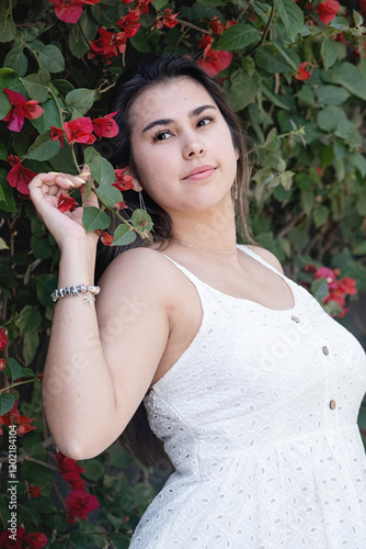 beautiful young woman wearing white summer dress surrounded by bougainvilia flowers photo