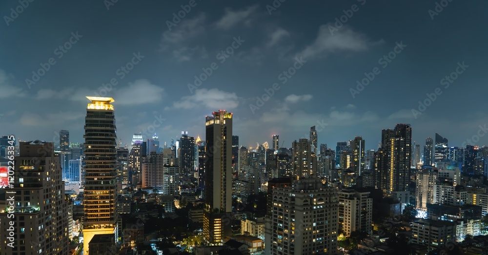 Vibrant city skyline of Bangkok illuminated by night as clouds drift above urban landscape and towering buildings