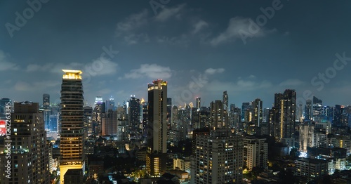Obraz na płótnie Vibrant city skyline of Bangkok illuminated by night as clouds drift above urban landscape and towering buildings w salonie