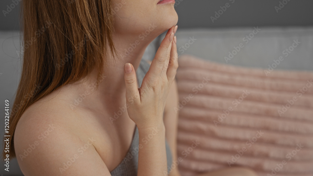 Young woman with caucasian features touching her chin thoughtfully while sitting in a cozy living room Young woman with caucasian features touching her chin thoughtfully while sitting in a cozy living room