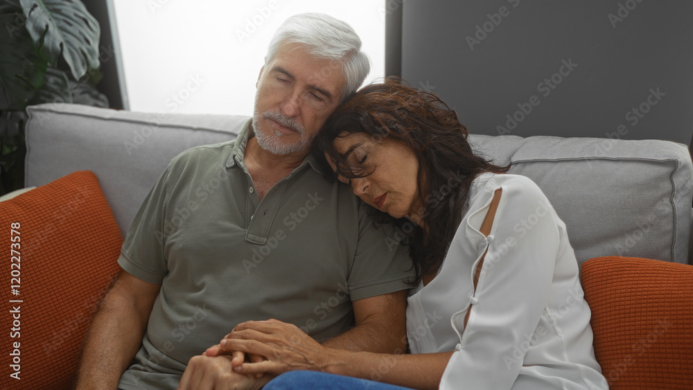 Fototapeta premium Middle-aged couple peacefully asleep on a cozy couch in a modern living room, reflecting comfort and togetherness in a warm home setting.