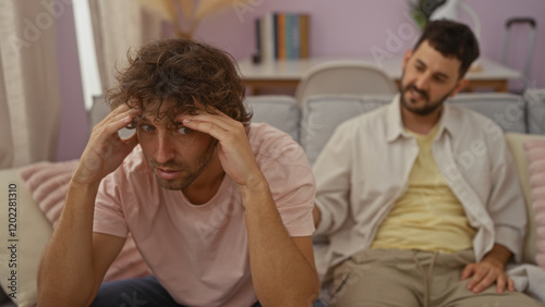 Men sitting in a cozy living room, one man looking stressed while the other offers support, symbolizing brotherly or family relationship in an indoor home setting
