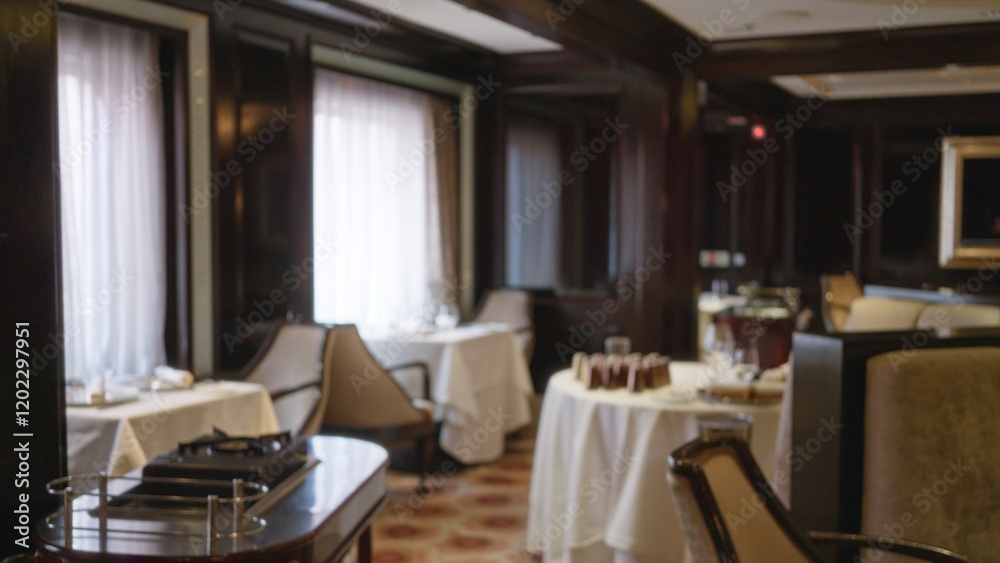 Fototapeta premium Blurred luxury restaurant interior with elegant decor and table settings, featuring warm lighting and plush seating for an upscale dining experience.