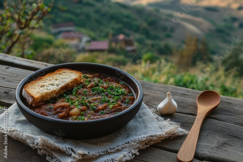 Bowl of soup with fresh green onions, garlic, and bread, outdoor setting