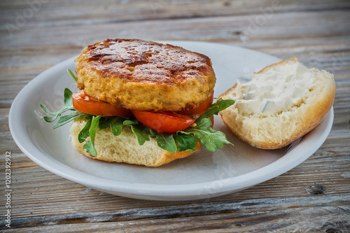 crab cake sandwich with arugula and sliced tomato