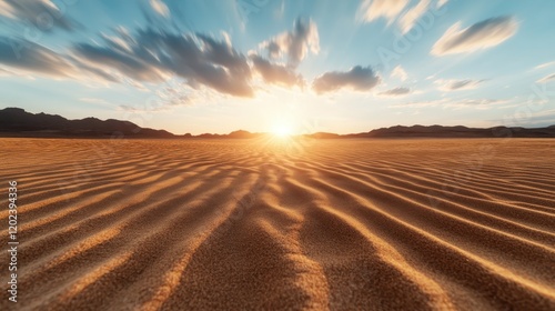 A stunning sunset casts golden hues over the sandy desert landscape, showcasing gentle waves of sand and a tranquil, expansive atmosphere inviting reflection.