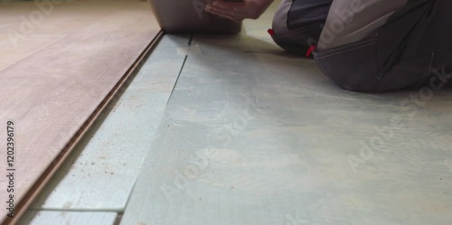 Construction worker installing laminate flooring plank