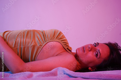 Photo of beautiful charming girl lying half-naked enjoying weekend, vacation free time at home. Neon background.