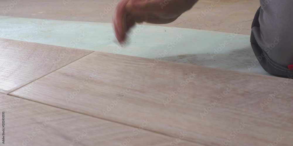 Construction worker installing modern laminate wood flooring