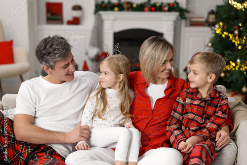 Happy family in pajamas on sofa at home. Christmas morning photo