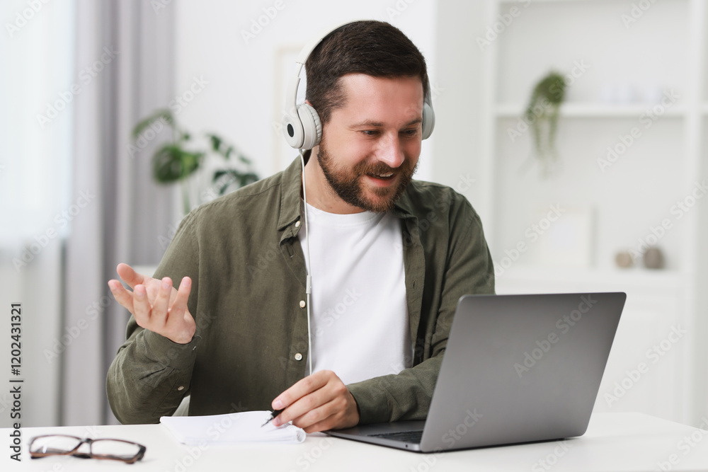 Naklejka premium Interpreter in headphones having video chat via laptop at white table indoors