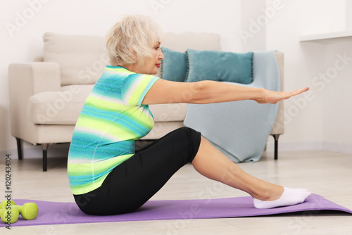 Senior woman exercising with fitness mat at home