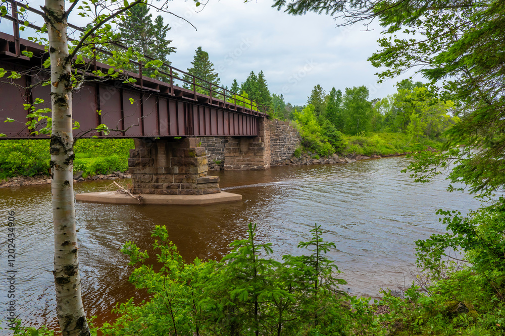 A steel bridge, supported by concrete and stone blocks, over a river in northern Minnesota.