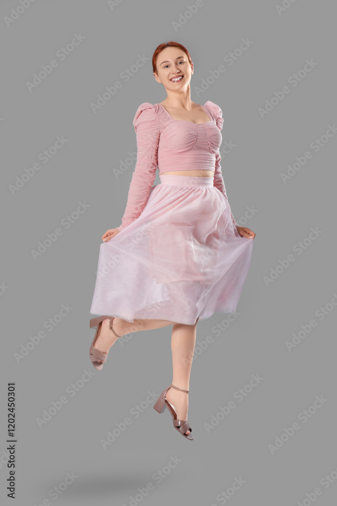 Naklejka premium Beautiful young woman jumping on grey background