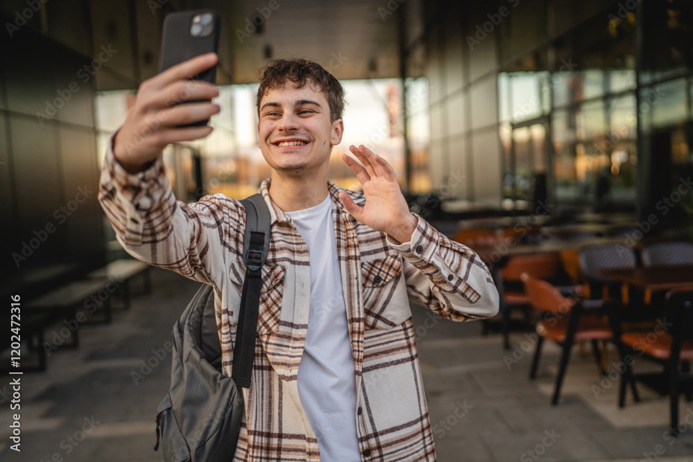 young man have video call on mobile phone while walk on the street