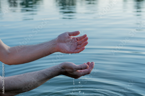 hands of the person in water on sunset	