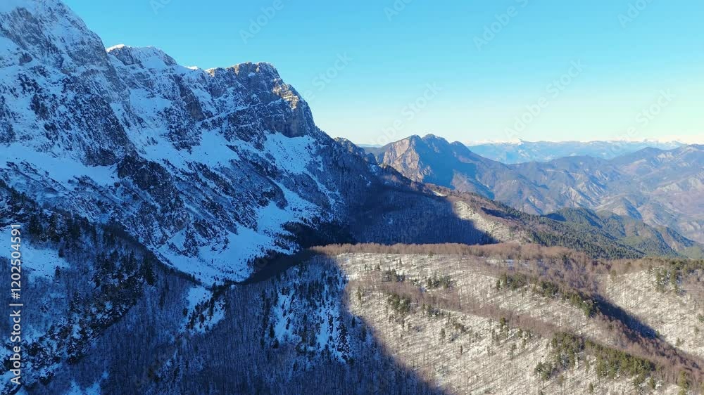 Snow covered peaks and valleys of Gyftokampos, Zagori, Greece Aerial tracking right reveals dramatic shadow and light contrast