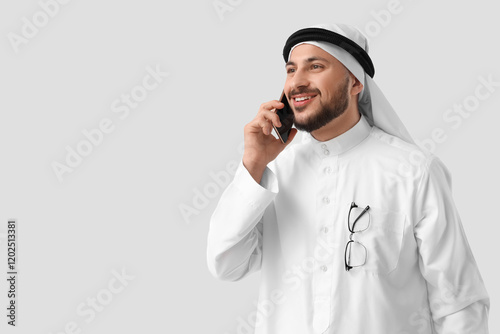 Arab businessman talking by mobile phone on light background