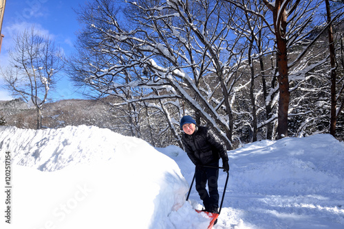 雪国でスノーダンプを使用して除雪をしている老人 photo