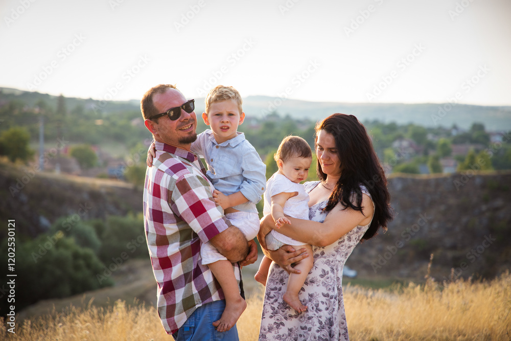 Fototapeta premium happy young family of four in summer at sunset
