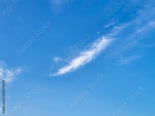 Feathery white fluffy clouds lie against a blue sky background photo