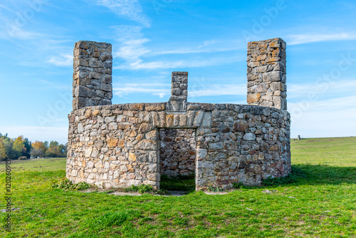 A stone structure standing in Horni Slavkov, which historically served as an execution ground, set against a clear blue sky and open field. Czechia photo