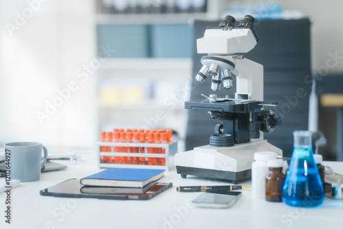 In an empty lab room with no people, a desk holds a blood tube, virus samples, and a monitor displaying blood cell analysis. A medical lab technician works with advanced equipment.