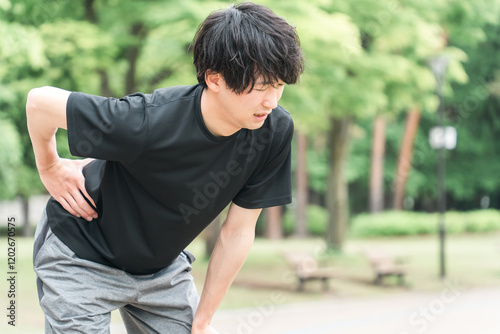 運動中に腰を抑える男性（腰痛・ぎっくり腰・ヘルニア・怪我・後遺症・リハビリ）
