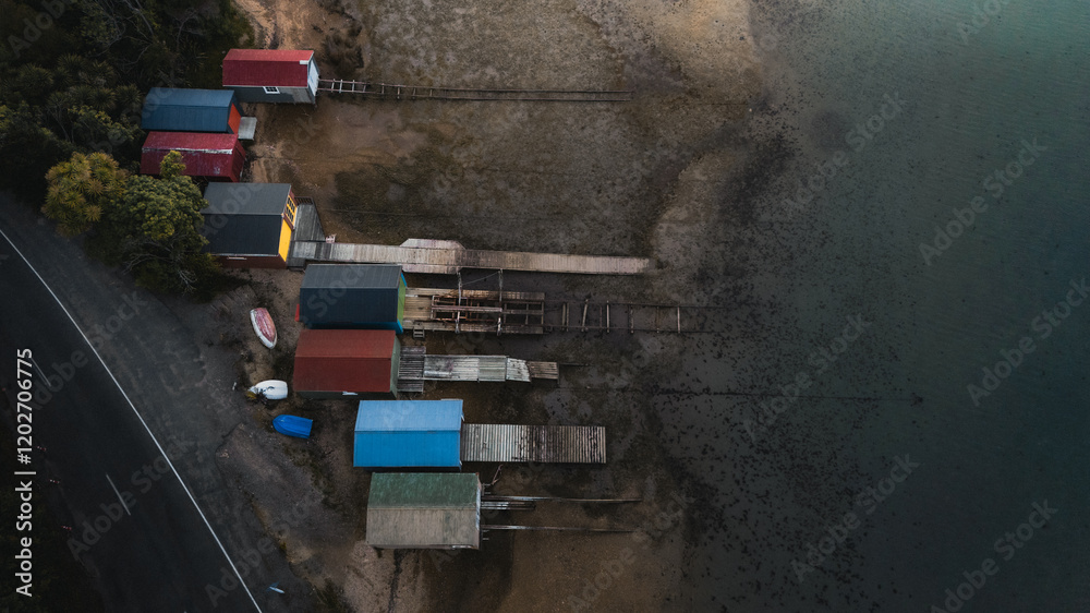 Obraz premium A top down drone shot of colorful fishing huts on the edge of the sea shore
