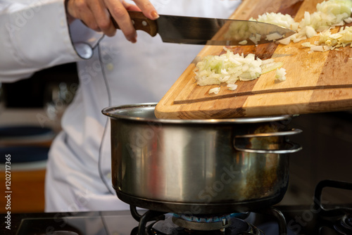 Fototapeta Naklejka Na Ścianę i Meble -  Chef adicionando cebola picada em panela no fogão