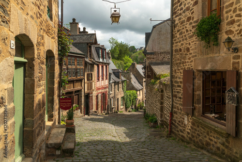 View of the medieval street of the city with half-timbered houses descending to the embankment of the Rance River on a sunny summer day, Dinan, Cotes-d'Armor, Brittany, France photo