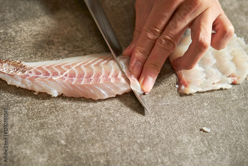 Close-up of hands cutting raw fish with sashimi knife photo