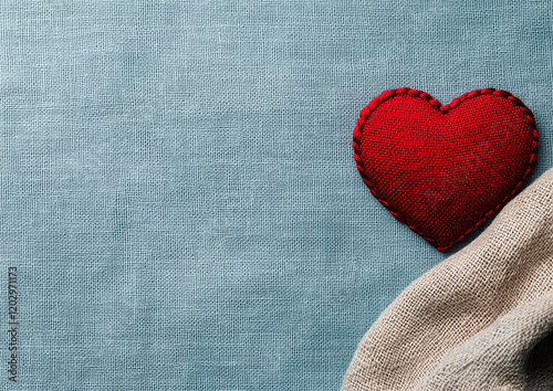 Red embroidered heart patch on textured blue fabric background with beige cloth accent