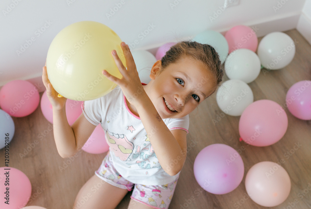 A surprised little girl with colorful balloons in pastel colors on a white background. Celebration, birthday, party, childhood concept. Top view A surprised little girl with colorful balloons in pastel colors on a white background. Celebration, birthday, party, childhood concept. Top view