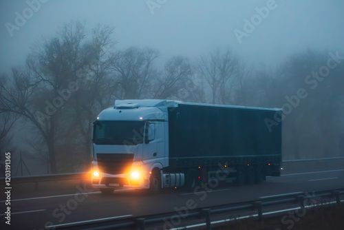 Truck driving on a highway on a day with adverse weather conditions due to fog, side view.