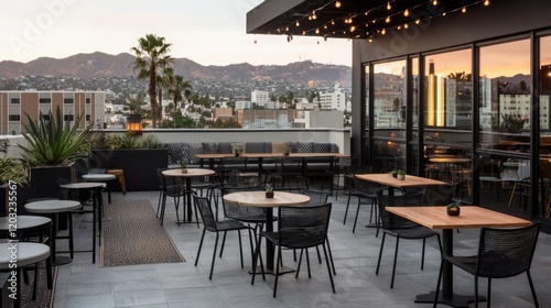 A stylish rooftop terrace featuring tables, chairs, and city views, adorned with string lights and surrounded by greenery.