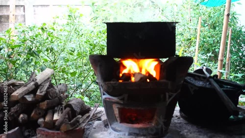 In a simple and old-fashioned way, cooking food with a stainless steel pot and an Anglo charcoal stove. to get a dark sooty color over a long time. The charcoal stove has a red light on it.