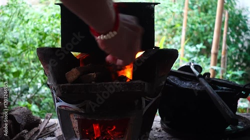 In a simple and old-fashioned way, cooking food with a stainless steel pot and an Anglo charcoal stove. to get a dark sooty color over a long time. The charcoal stove has a red light on it.