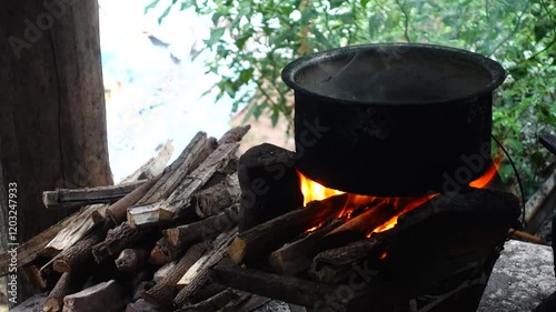 In a simple and old-fashioned way, cooking food with a stainless steel pot and an Anglo charcoal stove. to get a dark sooty color over a long time. The charcoal stove has a red light on it.