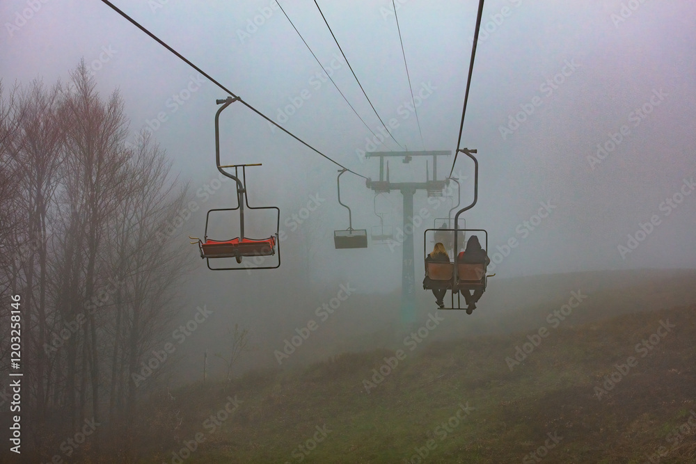 Silent journey through the misty mountains at dusk with empty and occupied lifts